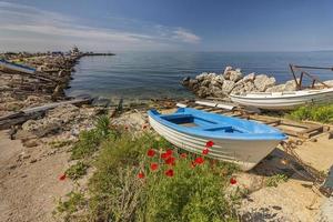 fishing boat on sea sand with blue sky and pier photo