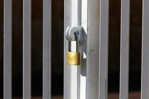 A rusty padlock hangs on a closed gate. photo