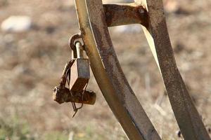 A rusty padlock hangs on a closed gate. photo