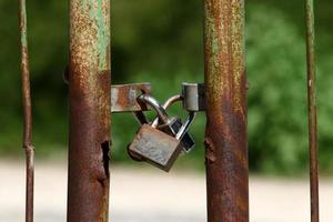 A rusty padlock hangs on a closed gate. photo