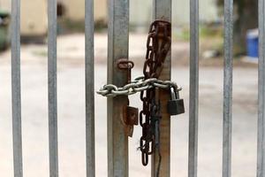 A rusty padlock hangs on a closed gate. photo