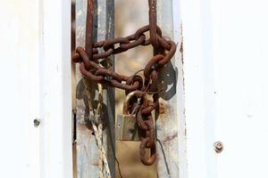 A rusty padlock hangs on a closed gate. photo