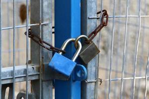 A rusty padlock hangs on a closed gate. photo