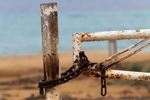 A rusty padlock hangs on a closed gate. photo