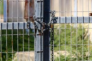 A rusty padlock hangs on a closed gate. photo