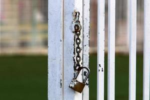 A rusty padlock hangs on a closed gate. photo