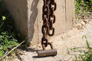 A rusty padlock hangs on a closed gate. photo