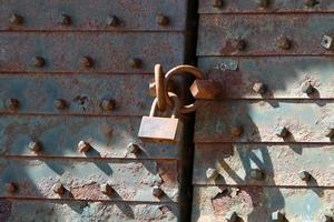 A rusty padlock hangs on a closed gate. photo