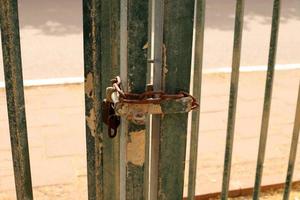 A rusty padlock hangs on a closed gate. photo