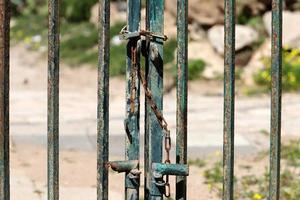 A rusty padlock hangs on a closed gate. photo