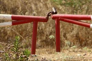 A rusty padlock hangs on a closed gate. photo