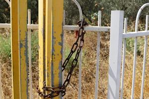 A rusty padlock hangs on a closed gate. photo