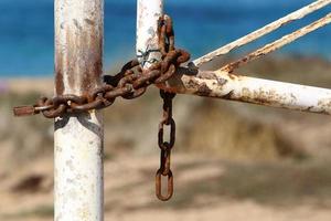 A rusty padlock hangs on a closed gate. photo