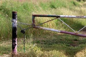 A rusty padlock hangs on a closed gate. photo