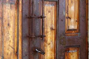 A rusty padlock hangs on a closed gate. photo