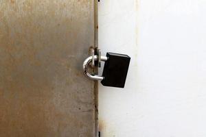 A rusty padlock hangs on a closed gate. photo