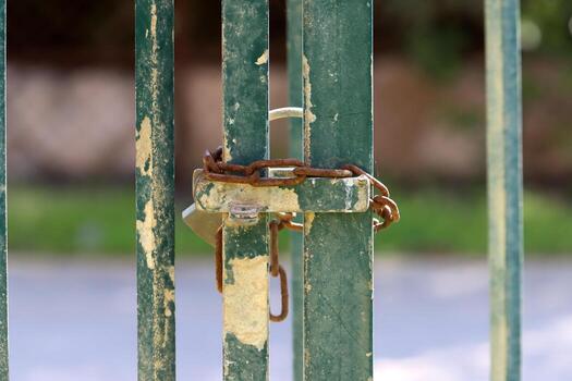 A rusty padlock hangs on a closed gate. photo
