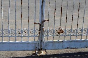 A rusty padlock hangs on a closed gate. photo