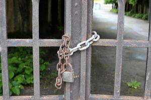 A rusty padlock hangs on a closed gate. photo