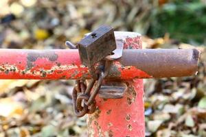 A rusty padlock hangs on a closed gate. photo