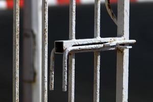 A rusty padlock hangs on a closed gate. photo