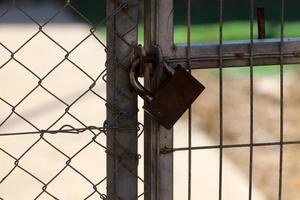 A rusty padlock hangs on a closed gate. photo