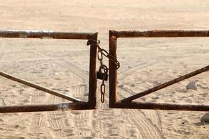 A rusty padlock hangs on a closed gate. photo