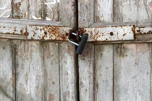 A rusty padlock hangs on a closed gate. photo