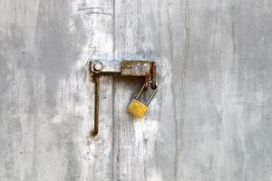 A rusty padlock hangs on a closed gate. photo