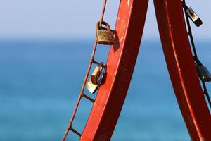 A rusty padlock hangs on a closed gate. photo