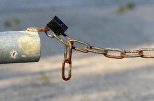 A rusty padlock hangs on a closed gate. photo