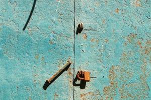 A rusty padlock hangs on a closed gate. photo