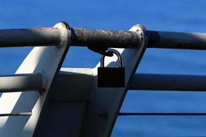 A rusty padlock hangs on a closed gate. photo