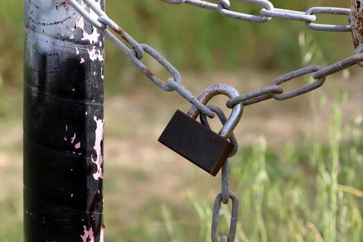 A rusty padlock hangs on a closed gate. photo