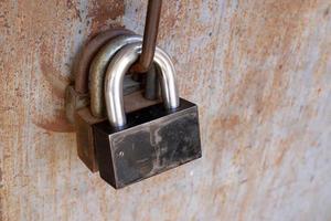 A rusty padlock hangs on a closed gate. photo