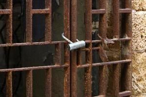 A rusty padlock hangs on a closed gate. photo