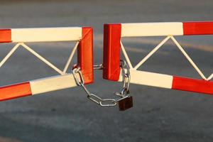 A rusty padlock hangs on a closed gate. photo