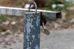 A rusty padlock hangs on a closed gate. photo