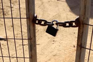 A rusty padlock hangs on a closed gate. photo