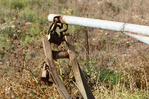 A rusty padlock hangs on a closed gate. photo