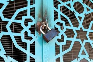 A rusty padlock hangs on a closed gate. photo