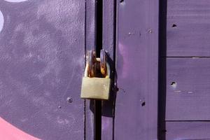 A rusty padlock hangs on a closed gate. photo