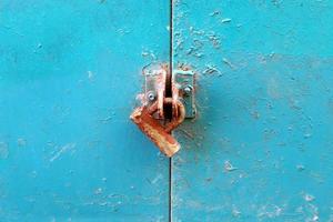 A rusty padlock hangs on a closed gate. photo