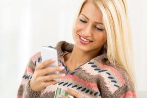 mujer joven sonriente que sostiene el teléfono móvil foto