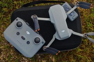 MALANG, INDONESIA - November 6th 2022, Top view of the grey DJI Mini 2 drone and remote above the bag and in nature photo