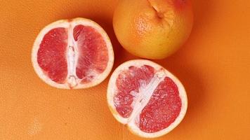 Sliced pink grapefruit on orange surface video