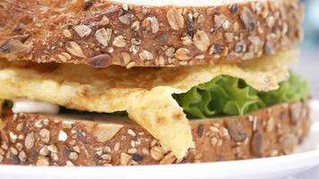 sándwich de huevo hecho con pan de trigo, tomate y lechuga en la mesa video