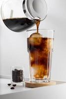 Pouring the espresso in cold water on a white table, Vertical photo