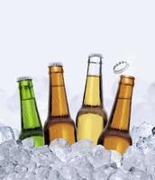 cuatro botellas de cerveza en cubitos de hielo aislado sobre fondo blanco. renderizado 3d foto