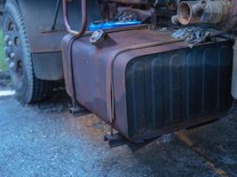 A large oil tank is attached to the side of an old, rusty car. photo